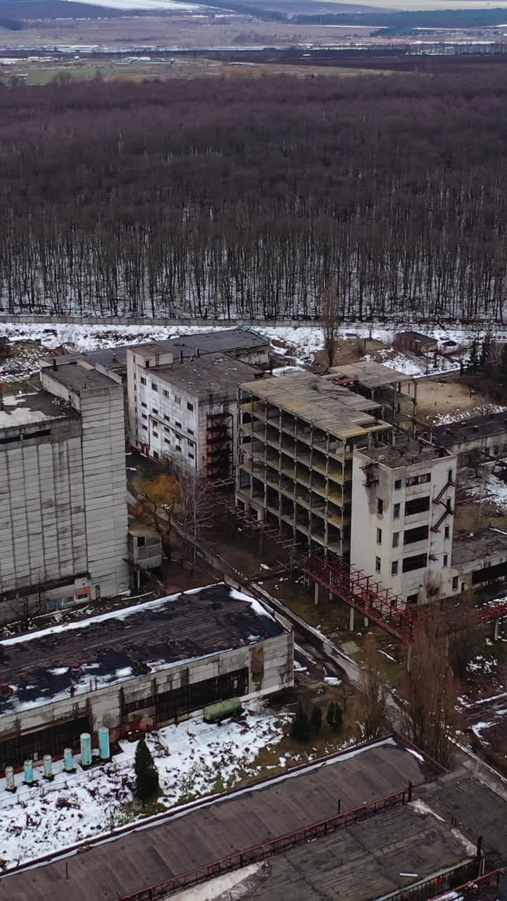Large territory of abandoned factory. Old industrial buildings for demolition. Ruined industrial zone on nature background. Aerial view. Vertical video