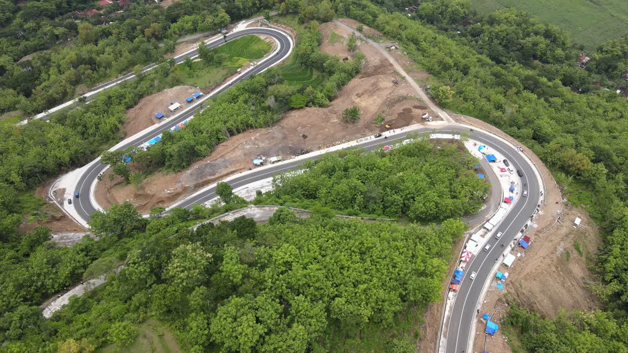 An aerial view showing a winding road through the mountains and forests in the Clongop area, Gunung Kidul, Yogyakarta.
