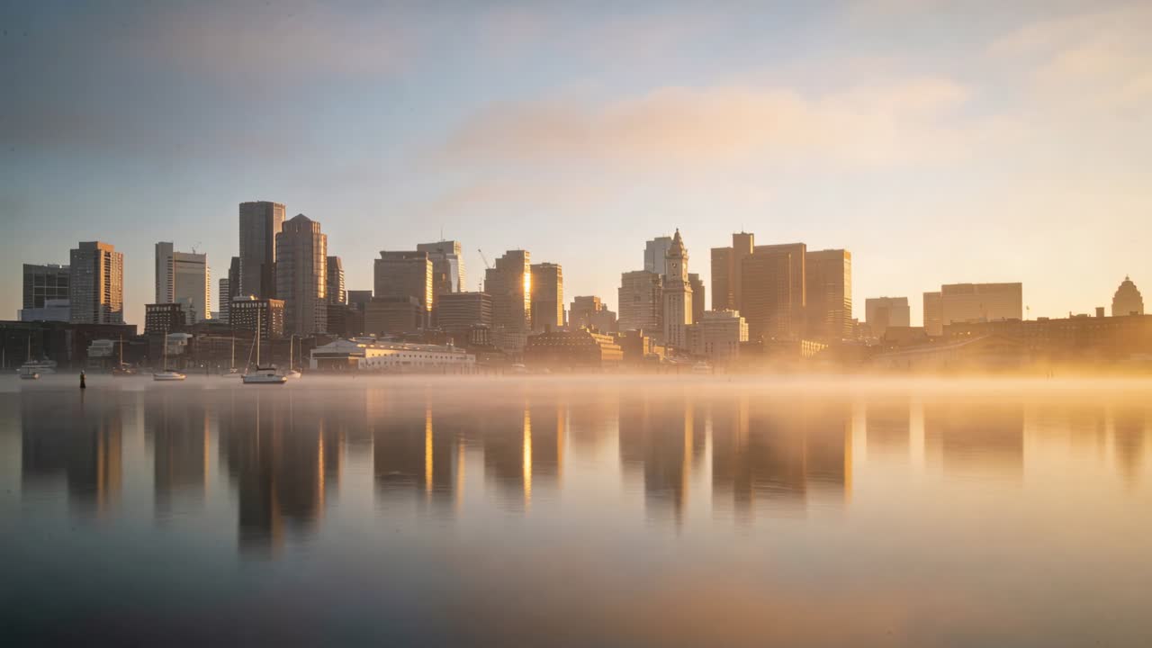 Sole nascente che riscalda lo skyline, nebbia che si dirada, riflessi che si allungano, barca a vela ferma per il settore immobiliare.