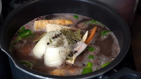 beef bone broth pan with herbs and vegetables slowly starts simmering, slow motion