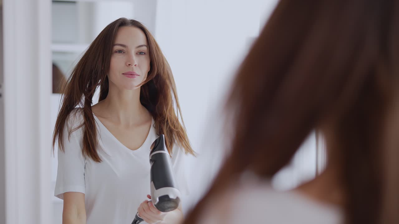 Mujer secándose el pelo frente a un espejo