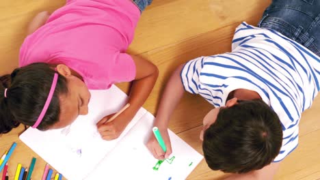 Cute-siblings-drawing-on-a-notebook-in-the-living-room