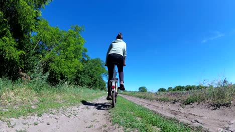 young woman riding vintage bicycle along a rural road in a village