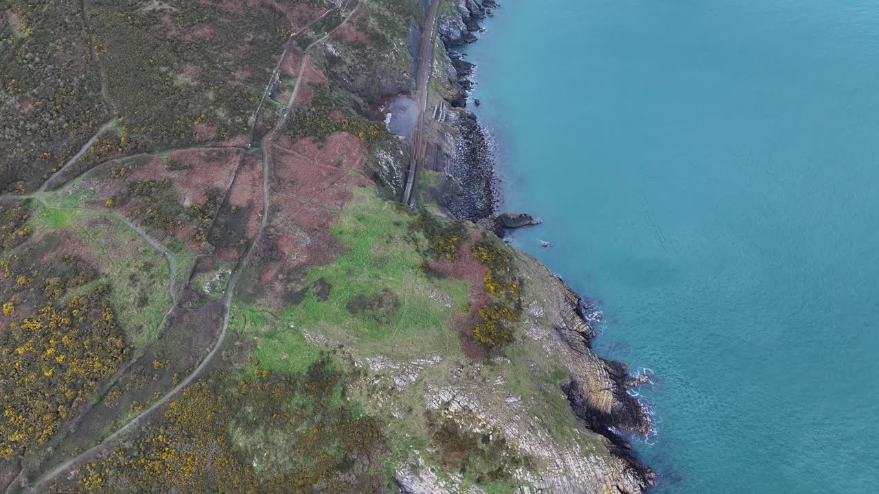 Naturskøn togrute i Irland. Toget kører ind i tunnelen ved Bray-kysten. Droneoptagelse fra luften