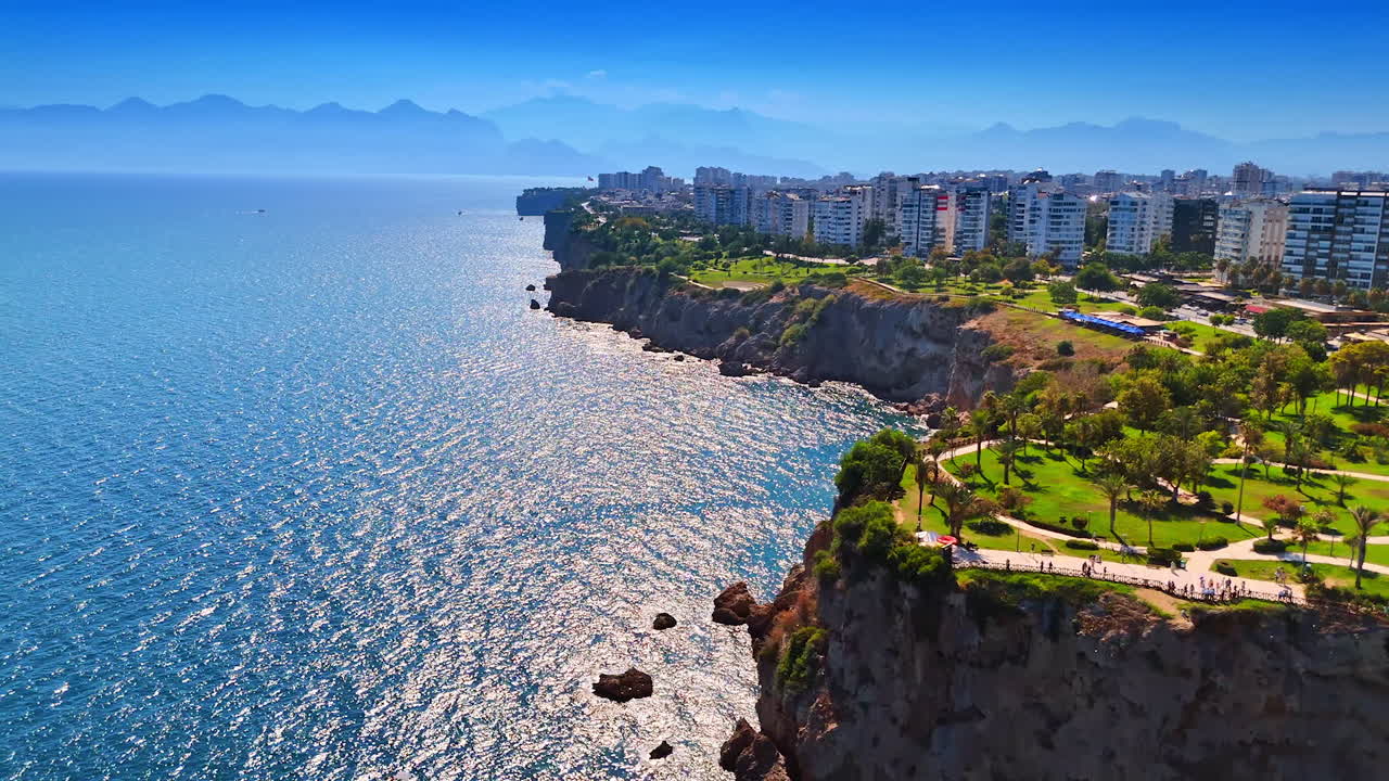Coastal view of the sea. Stunning coastline features rocky cliffs and lush green parks along the Mediterranean in a sunny urban setting