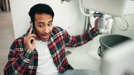 man fixing sink while talking on the phone