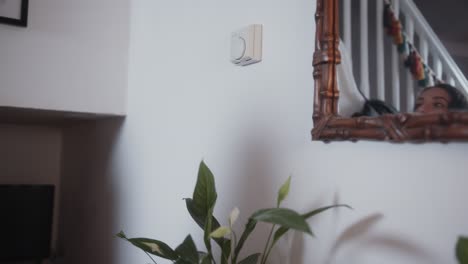 mujer ajustando el dial en el termostato, bajando la temperatura para ahorrar en facturas de energía durante la crisis del costo de la vida