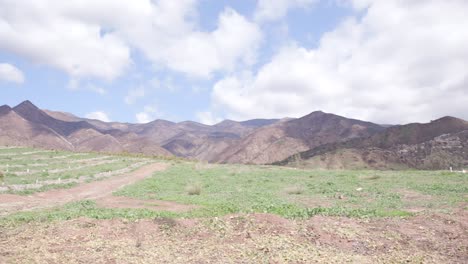 Toma-Panorámica-De-Un-Campo-Con-Montañas-Y-Nubes-4k