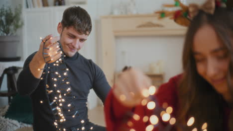 hombre clasificando luces iluminadas enredadas con amigos