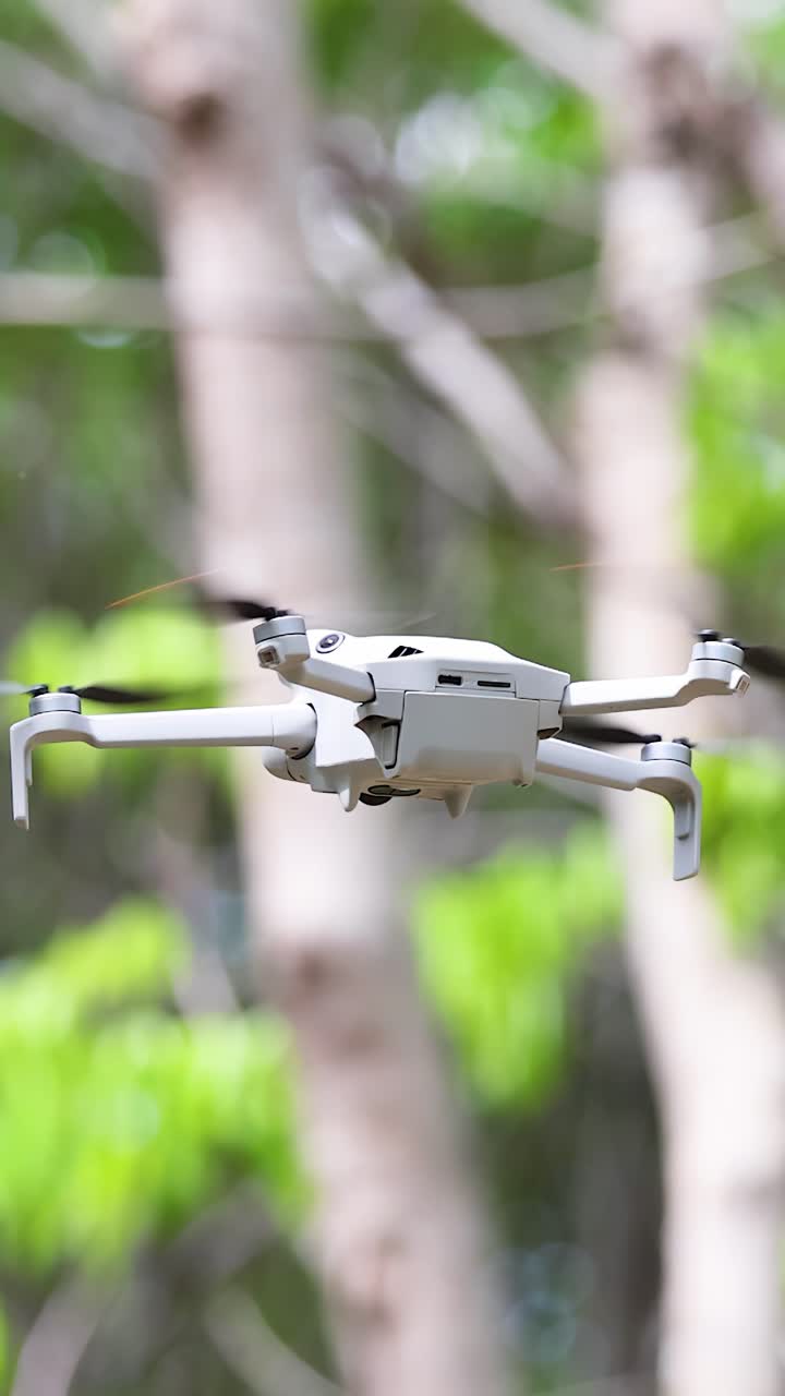 Drone bianco moderno che sorvola all'aperto con alberi verdi