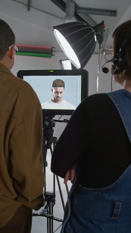 video vertical de una directora de cine y su asistente viendo la actuación de un actor en el monitor grabando una película en el estudio filmada en tiempo real