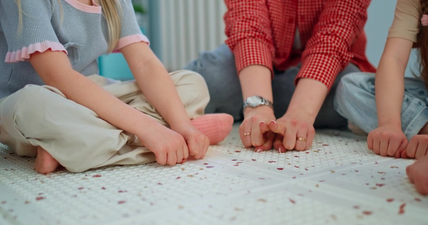 Adult and Children Playing a Hand Game on the Floor