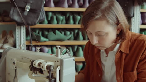 woman using sewing machine in shoemakers workshop