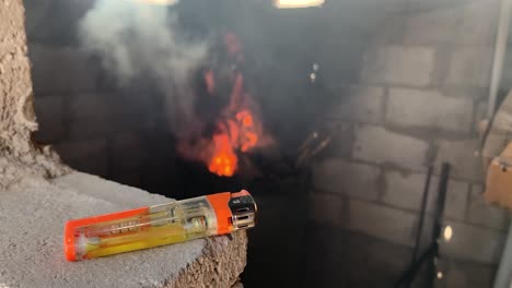 a gas lighter with a burning flame in the stove in the background