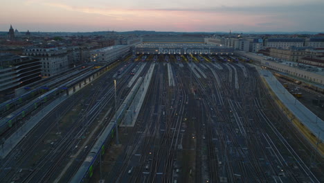 Forwards-fly-above-commuter-train-approaching-Roma-Termini-train-station.-Extensive-railway-tracks-in-city-at-dusk.-Rome,-Italy