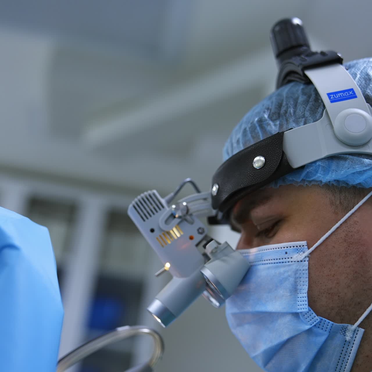 Otorinolaringoiatra osserva l'area operata attraverso gli occhiali del dispositivo. Medico con mascherina che parla durante l'operazione. Primo piano del ritratto