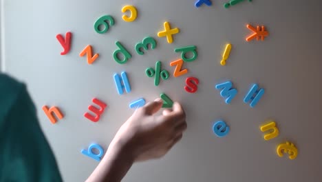 child playing with magnetic letters on refrigerator