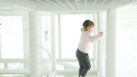 3-Year-Old-Toddler-Girl-Cautiously-Walking-Inside-the-Rope-Maze-for-Children-in-slow-motion,-rear-view