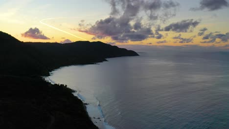 aerial drone footage of the tranquil caribbean sea near st. croix, usvi, with a stunning colorful sky illuminating a lush peninsula and calm shoreline in peaceful early light