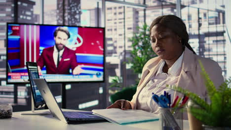 businesswoman reviewing documents in a modern office with news broadcast on screen