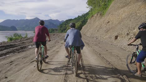 men cycling on a dirt road through a scenic mountain landscape