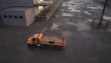 orange dump truck loaded with gravel parked outside of a factory