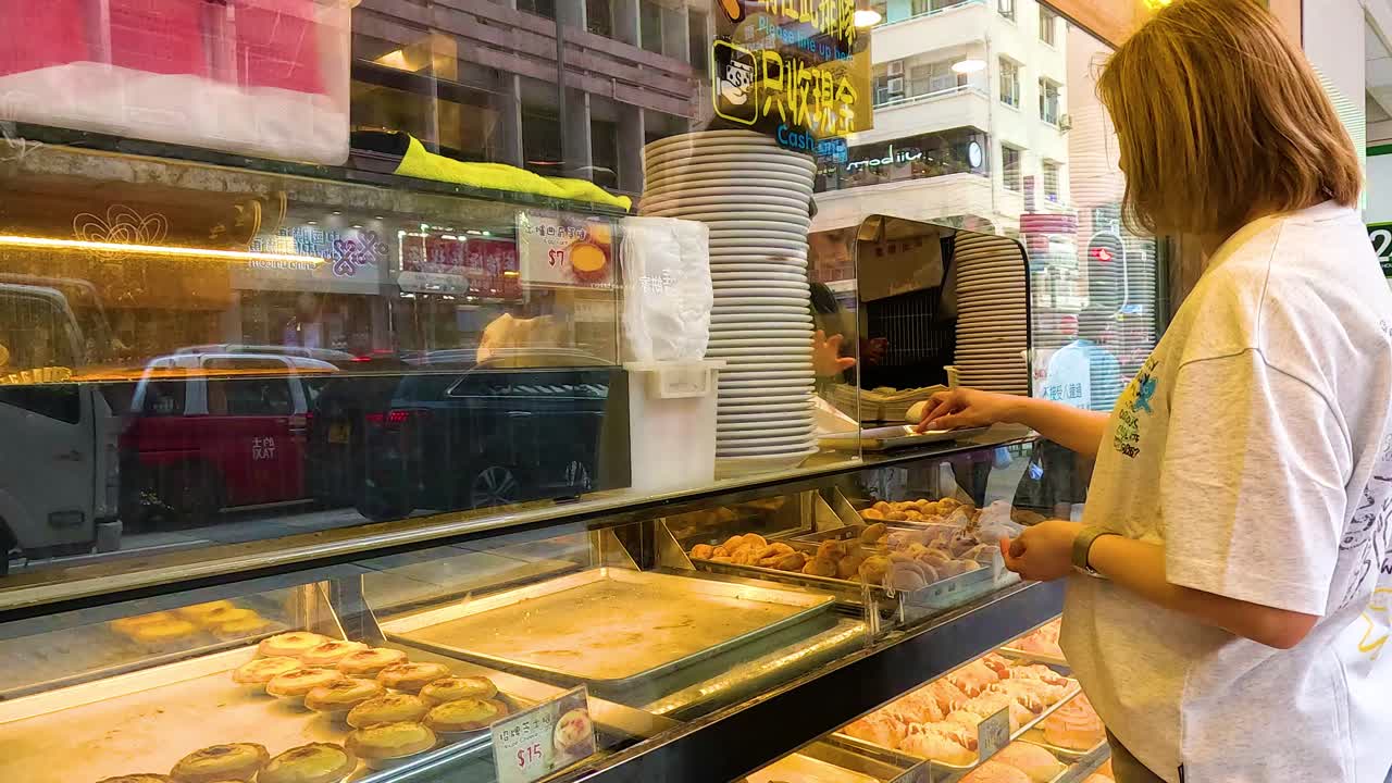 una mujer comprando pasteles en una panadería de hong kong.