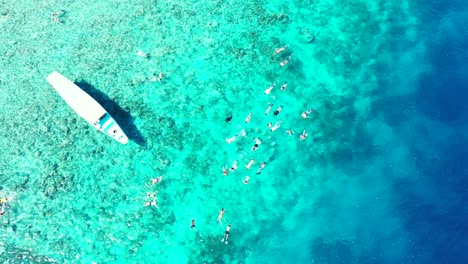 Snorkeling-at-the-Turtle-Bay-in-Perhentian-Island,-crystal-clear-turquoise-water-boats-and-a-large-group-of-tourists