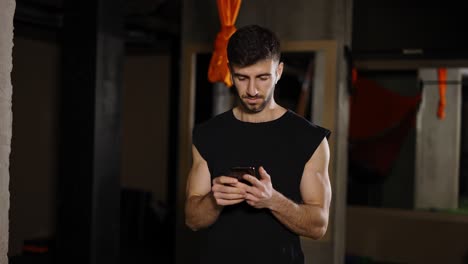 young man use phone at dark gym