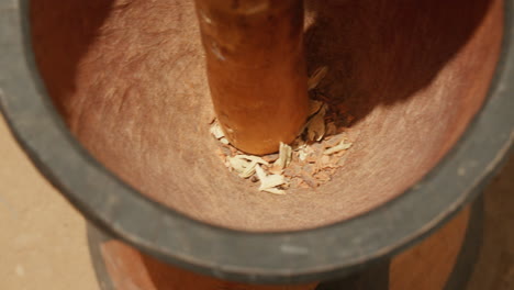 close-up of wooden pestle crushing herbs in a mortar