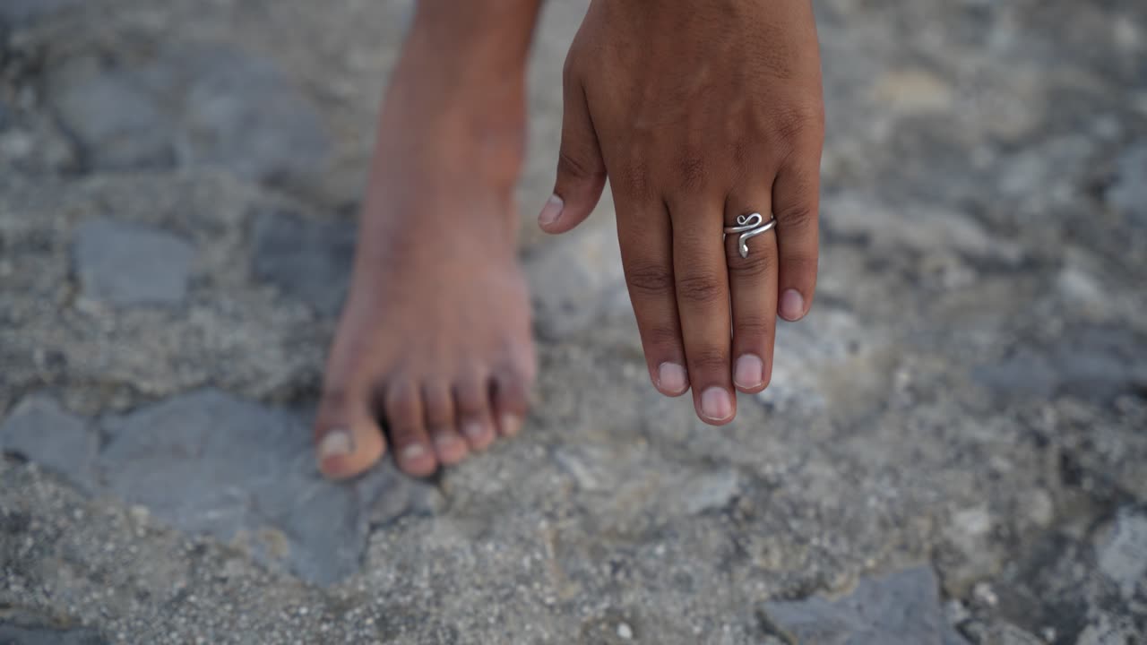 Shallow depth of field of unrecognizable Indian hand in motion of doing a pose for hatha yoga touching the ground with palm landing next to feet