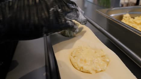 el chef aplica el relleno de patatas y queso a la masa de pierogi