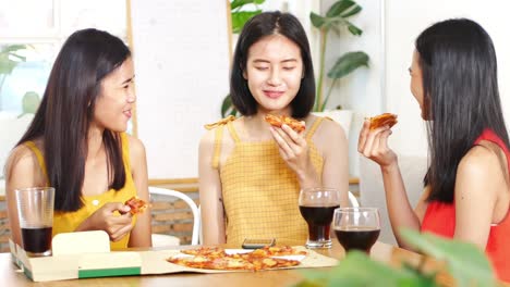 젊은 아름다운 아시아 여성 그룹이 피자를 먹고 레스토랑에서 그들의 일반적인 행복한 주제에 대해 이야기합니다.