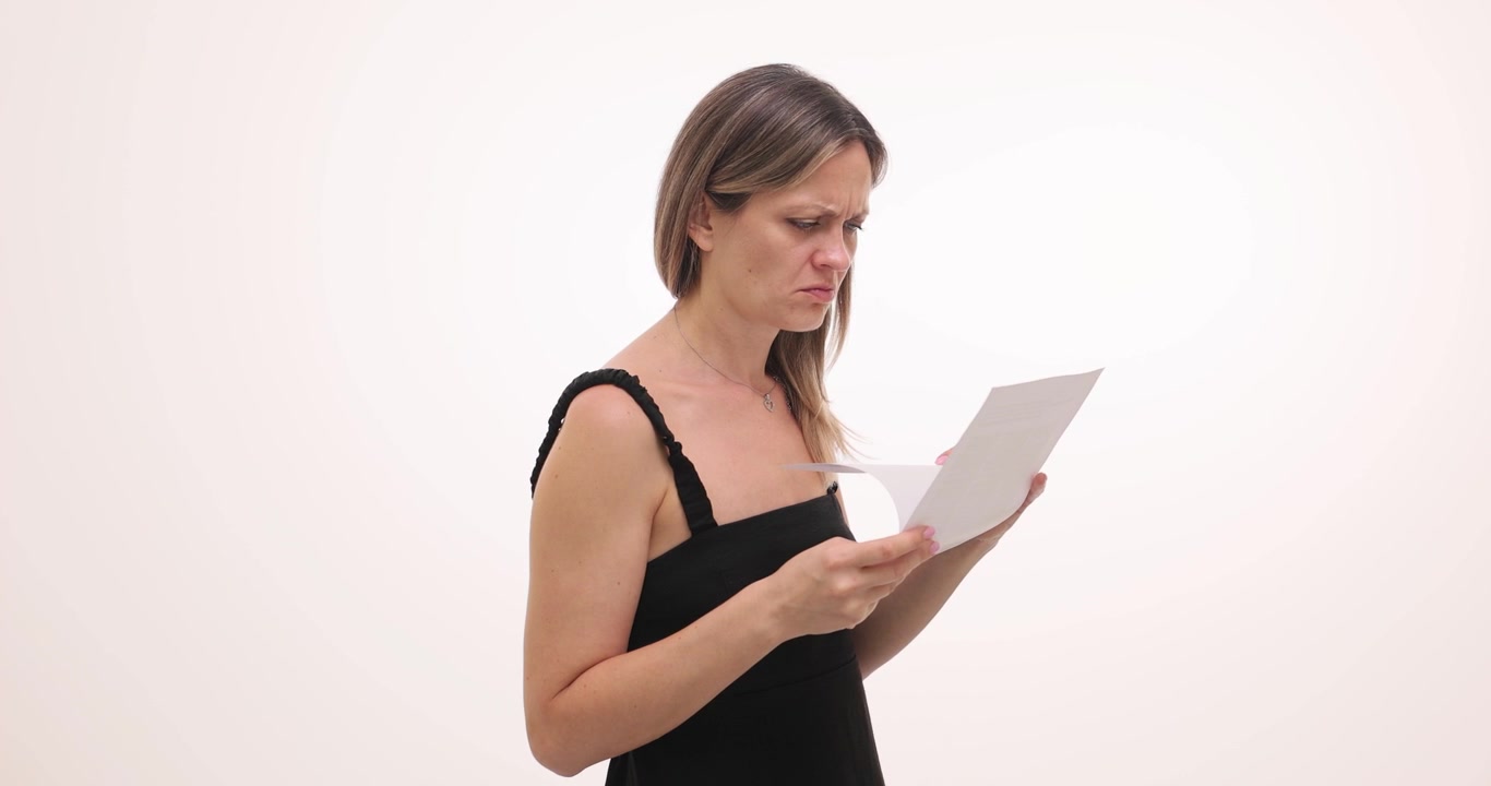 Donna guarda un foglio con espressione sorpresa e contrariata