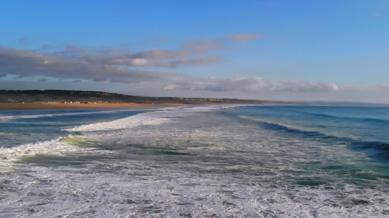 imágenes de drones del agua espumosa de las olas que ruedan en la costa de caparica en portugal