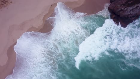 toma aérea giratoria de arriba hacia abajo de olas salvajes en praia da ursa, portugal