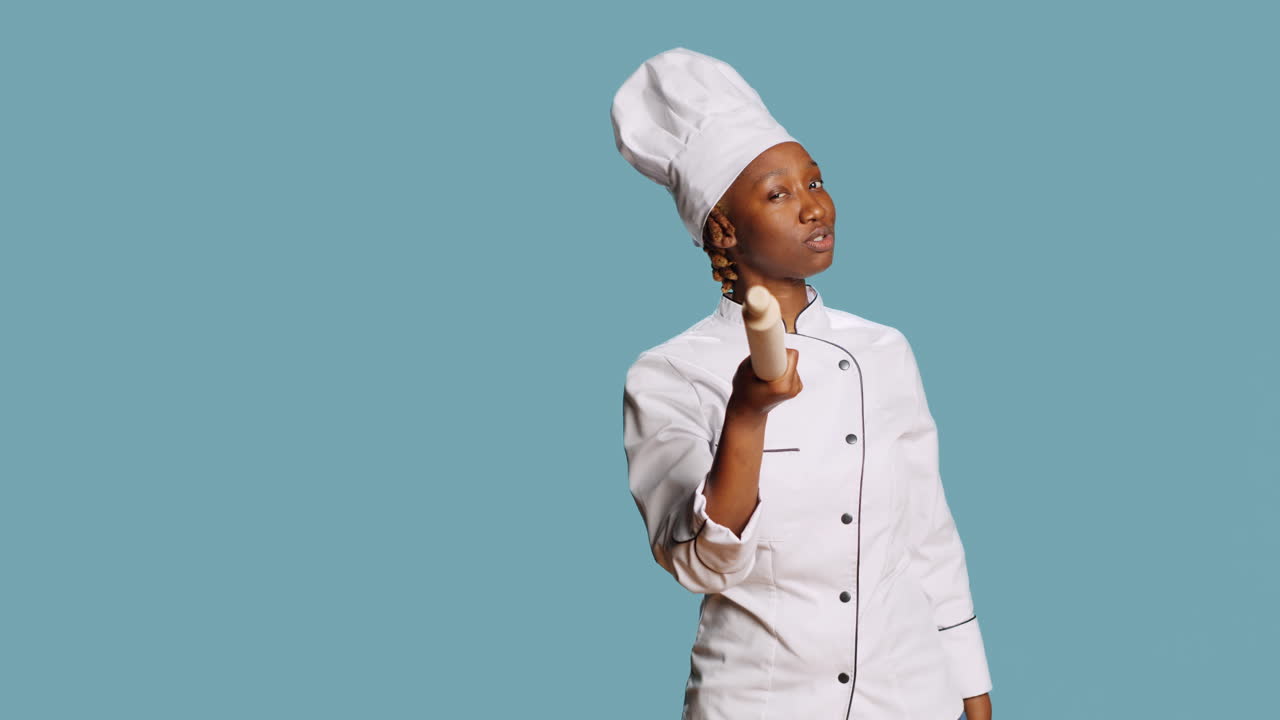 Chef afroamericano che indica la fotocamera con un matterello