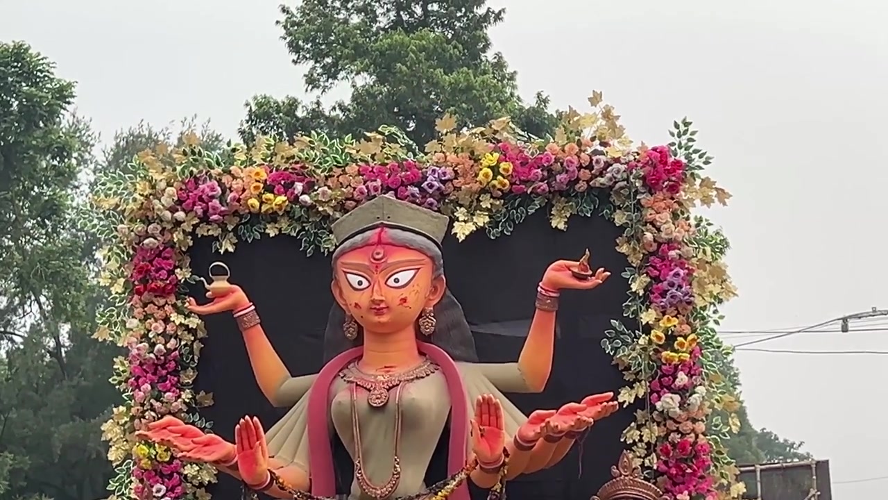Ídolo de Maa Durga em um pequeno caminhão, com fundo preto, decorações de flores, árvores, vegetação e céu azul