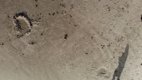 top down view of descent from 20 feet to 2 feet above sand with pilot shadow lowering down to a point where a tire track is