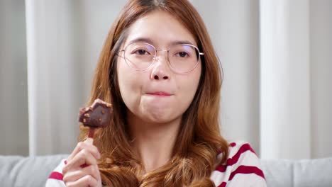 asian young woman in glasses tasting chocolate ice cream