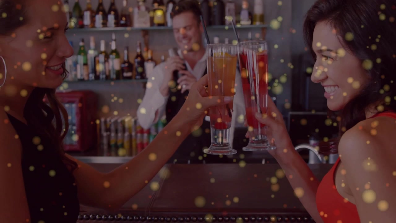 To kvinder skåler med cocktails ved en bardisk