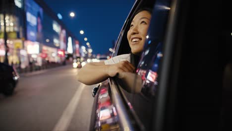 chinese woman riding in the car at night and admiring the city