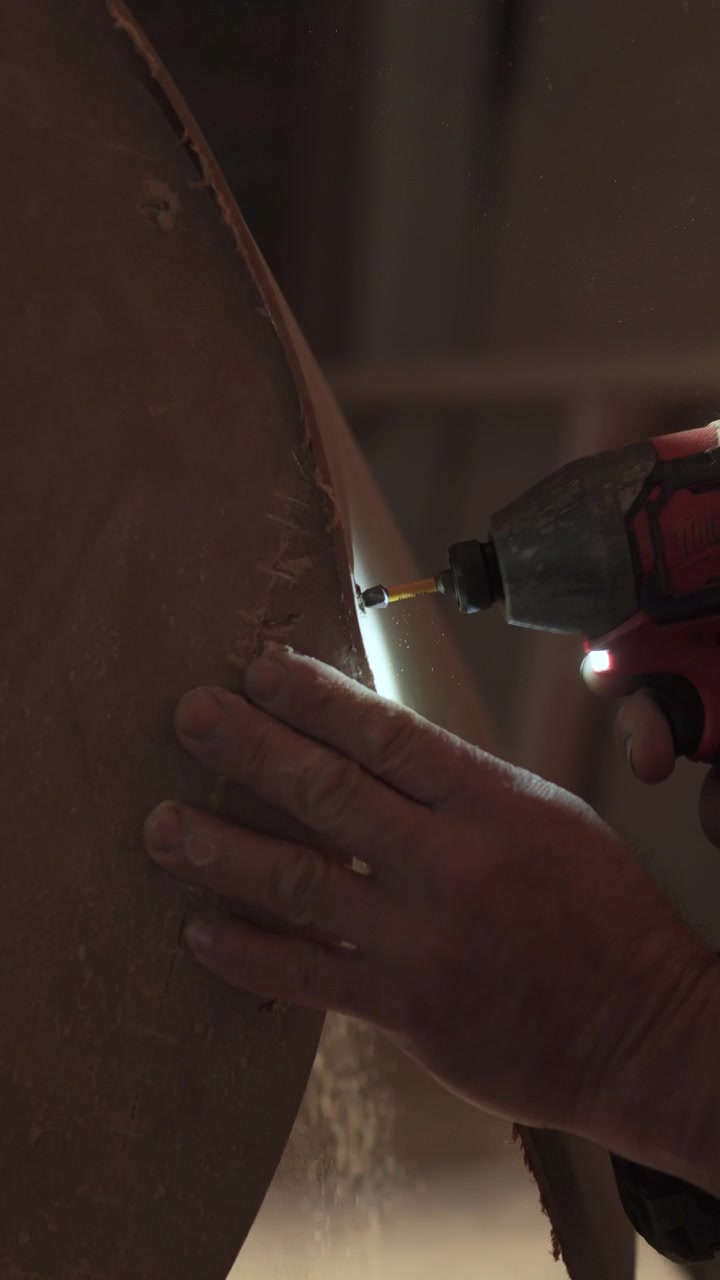 Primo piano che mostra una mano che tiene il pezzo mentre la vite viene inserita nella superficie curva usando un cacciavite con luce integrata.