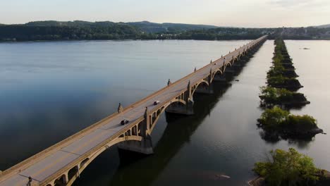 dolly forward drone shot of susquehanna river at sunset with traffic, old bridge piers remain after bridge burned in us civil war