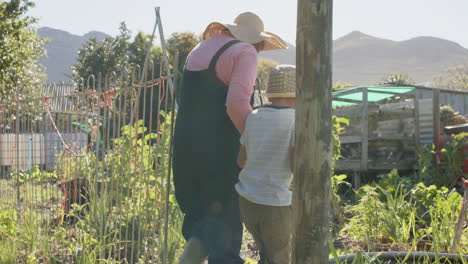 Senior-biracial-grandmother-and-grandson-walking-in-sunny-garden,-slow-motion