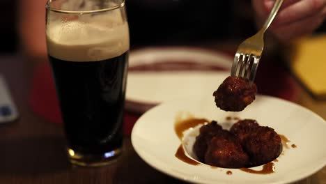 persona comiendo albóndigas con una cerveza fuerte