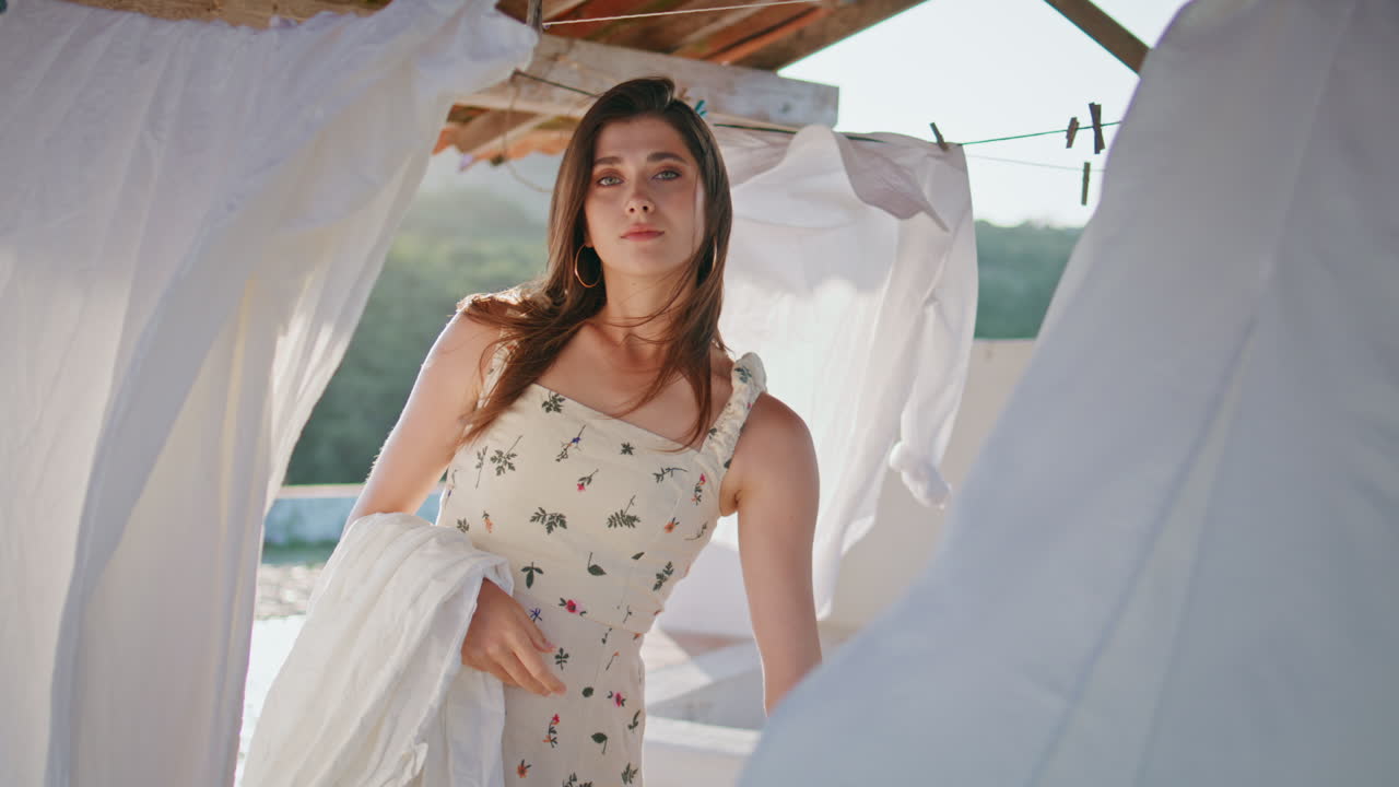 mujer sensual sosteniendo la ropa posando en la terraza de verano de primer plano. mujer mirando a la cámara