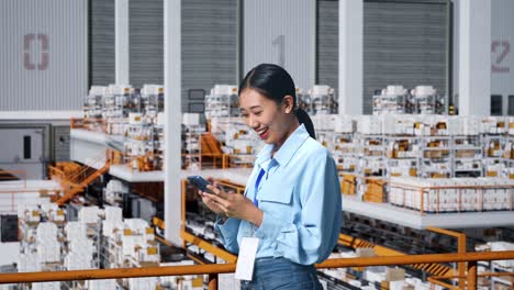 side view of asian business woman using mobile phone in the warehouse