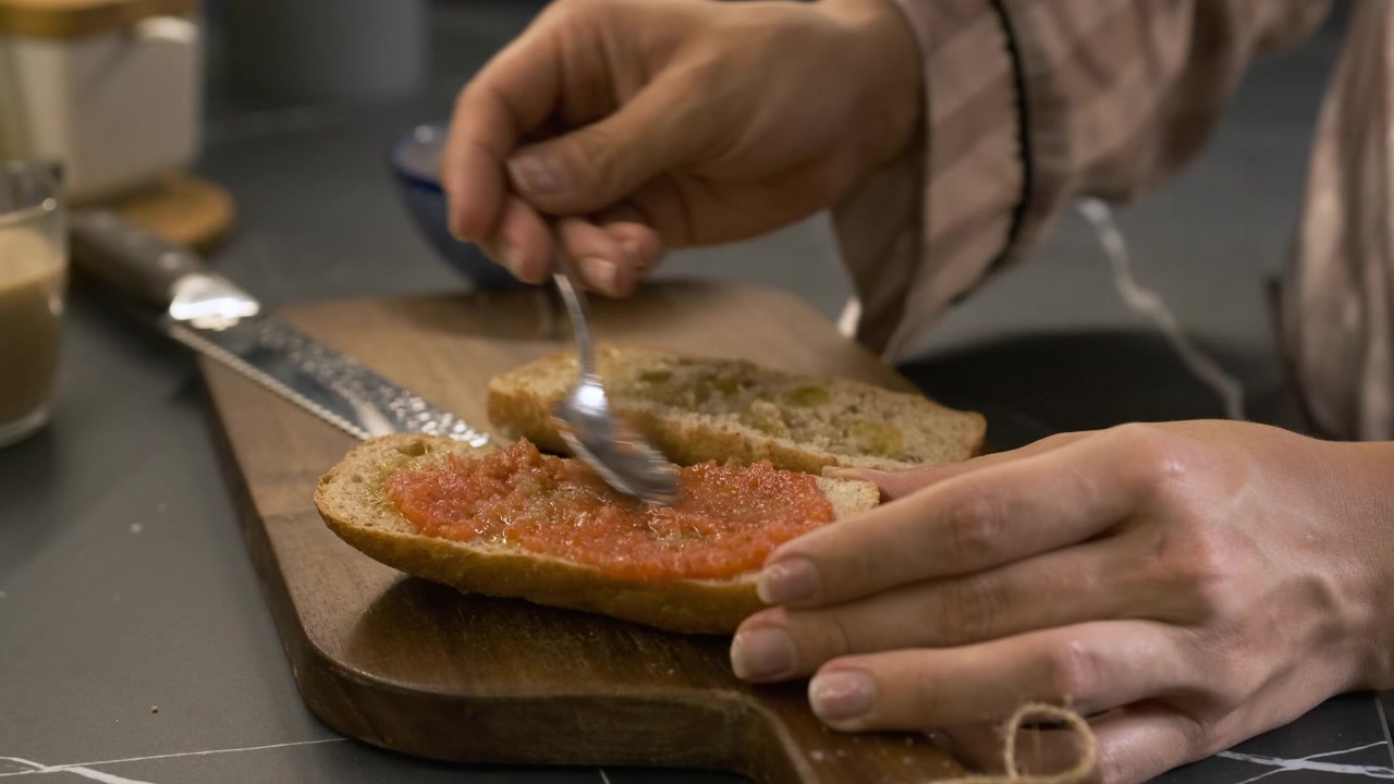 Persona che spalma passata di pomodoro su pane tostato