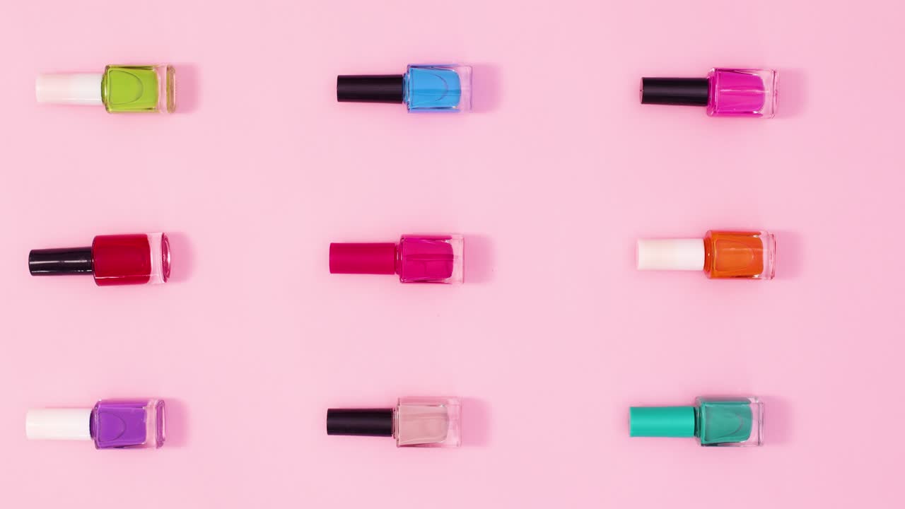 manicure botellas de esmalte de uñas patrón de diseño mover a la izquierda a la derecha en fondo rosa pastel. detener el movimiento